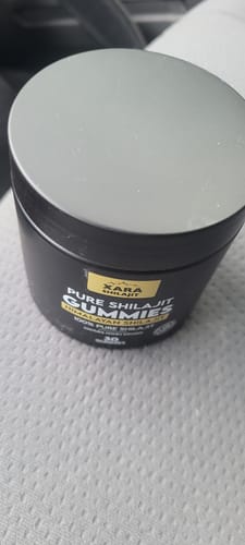 Customer's black tub of XARA SHILAJIT Pure Shilajit Gummies with a silver lid, shown up close on a textured surface.